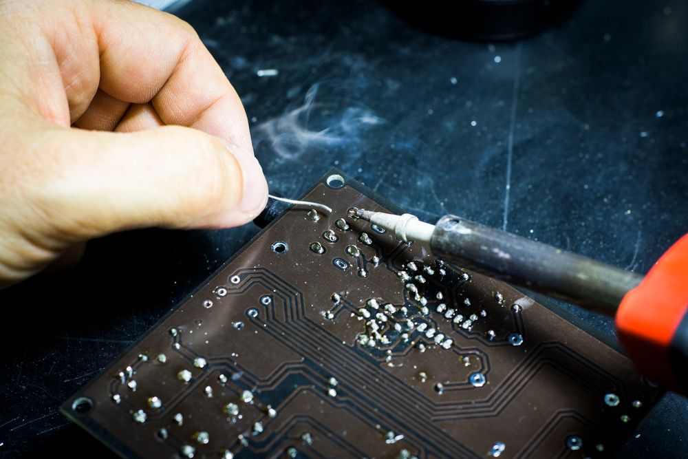 An engineer hand-soldering a circuit board