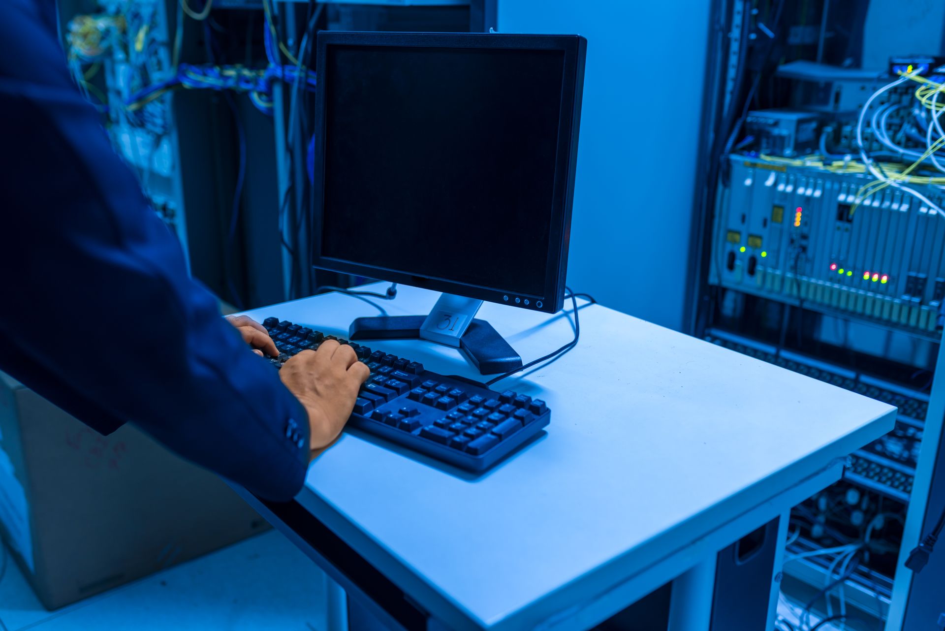 Engineer working at a network operations workstation with rack equipment behind